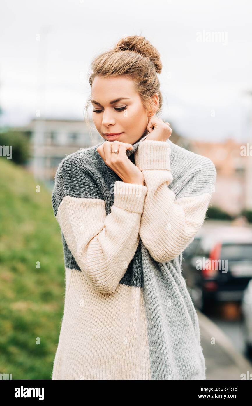 Portrait d'extérieur de la jeune jolie femme portant un pull gris chaud à col haut, temps froid Banque D'Images