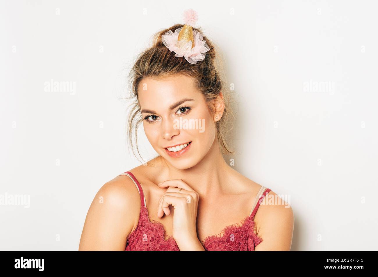 Studio photo de belle jeune femme aux cheveux blonds, chignon petit pain, portant le dessus de cami rose, posant sur fond blanc Banque D'Images