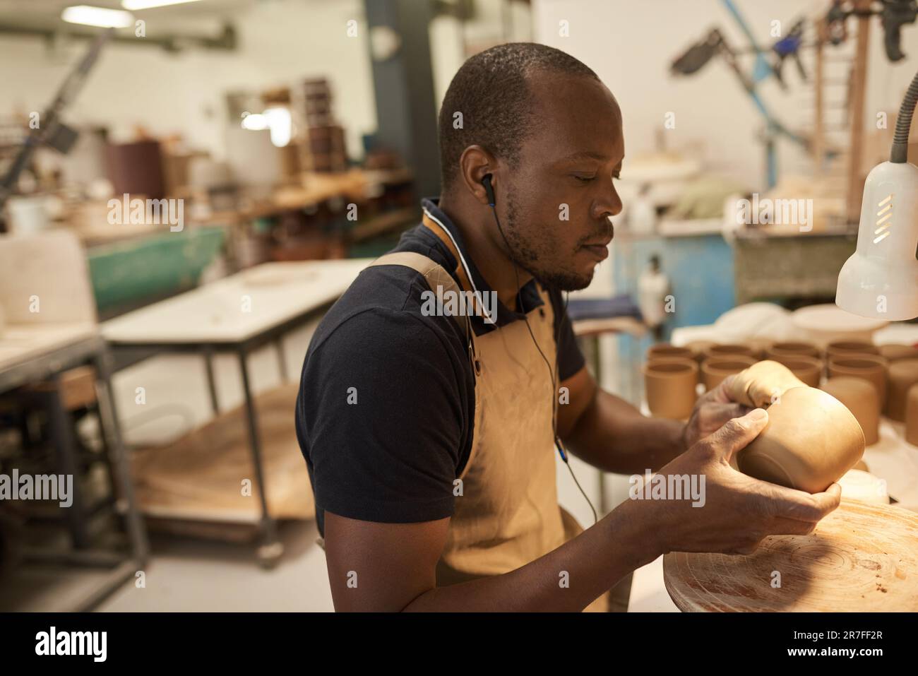 Céramiste africain travaillant sur un bol d'argile à un banc de studio Banque D'Images