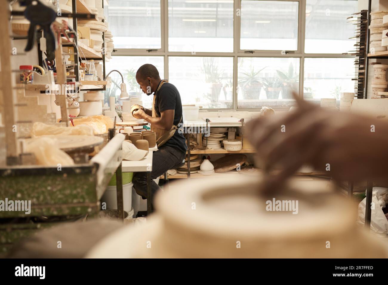African potter travaillant sur un bol à un banc dans un studio de céramique Banque D'Images