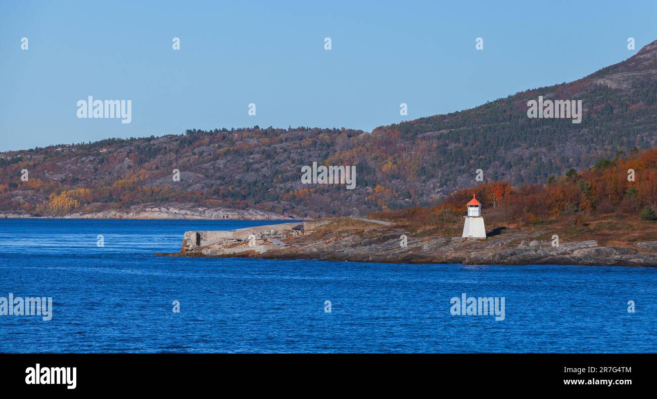 Tour de phare blanc avec sommet rouge se dresse sur une côte rocheuse de mer. Paysage norvégien panoramique Banque D'Images