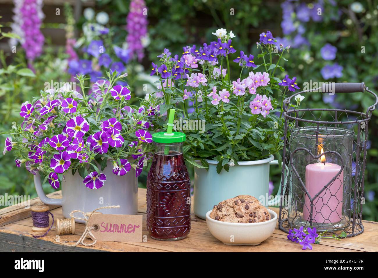décoration de table avec bouteille de jus, biscuits et fleurs d'été dans des pots en émail Banque D'Images