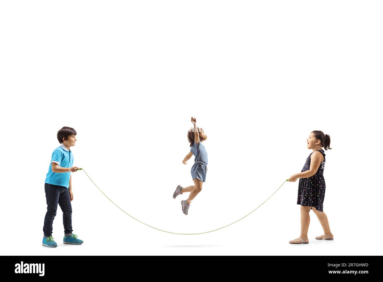 Photo de profil pleine longueur d'un garçon et de deux filles jouant la corde à sauter isolée sur fond blanc Banque D'Images