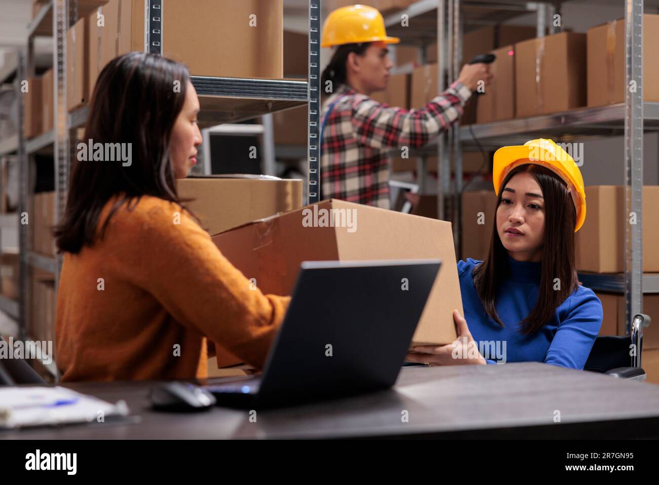 Les employés des magasins asiatiques vérifient la qualité des emballages de boîtes et gèrent les expéditions. Le préparateur de colis et l'opérateur postal du centre de distribution préparent le carton pour la livraison à l'entrepôt Banque D'Images