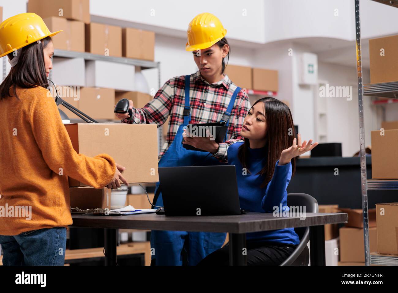 Les collaborateurs de l'industrie de la vente au détail gèrent l'expédition des colis dans la salle de stockage. Les employés asiatiques travaillent en équipe à l'aide d'un lecteur de code-barres sur une boîte de carton lors de l'expédition au bureau de l'entrepôt Banque D'Images