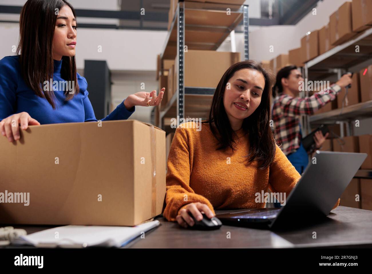 Entrepôt deux femmes asiatiques planifiant la livraison des paquets sur ordinateur portable. Les employés de l'entrepôt d'affaires vérifient la gestion des stocks de marchandises sur l'ordinateur dans la salle de stockage Banque D'Images