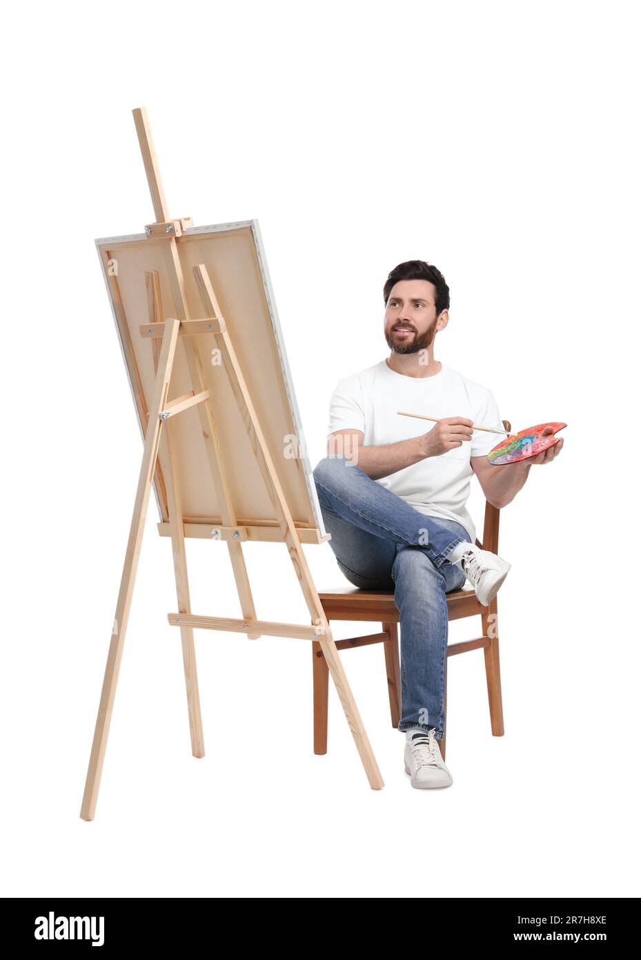 Homme avec peinture au pinceau sur fond blanc. Utilisation du chevalet pour tenir la toile Banque D'Images
