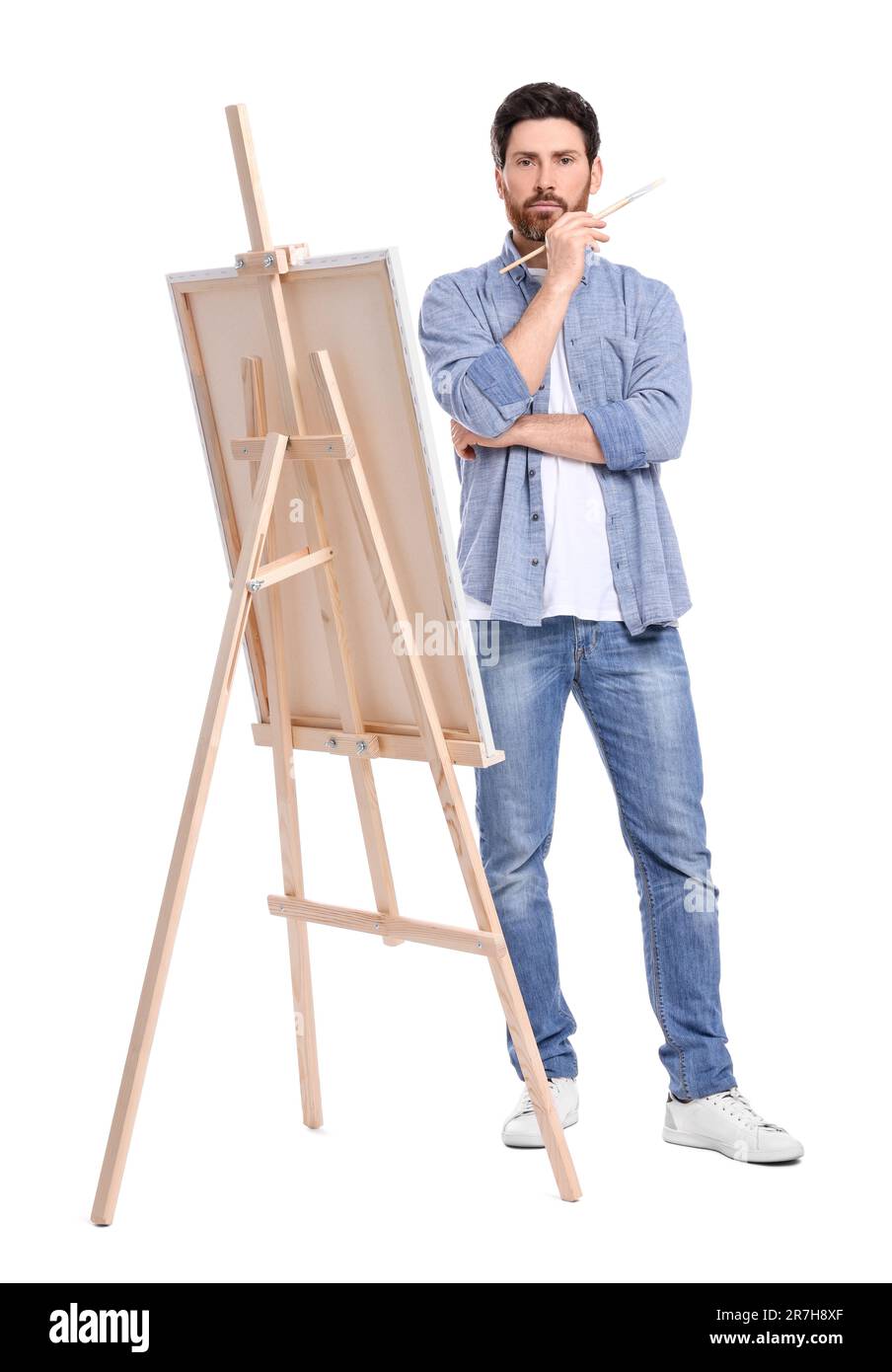 Homme peignant avec un pinceau sur fond blanc. Utilisation du chevalet pour tenir la toile Banque D'Images