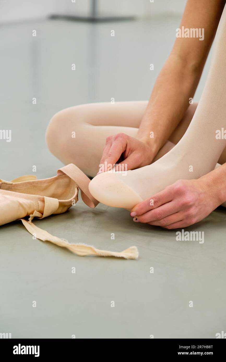 Ballerine mettant sur le ballet pointe chaussures assis sur le sol. Banque D'Images