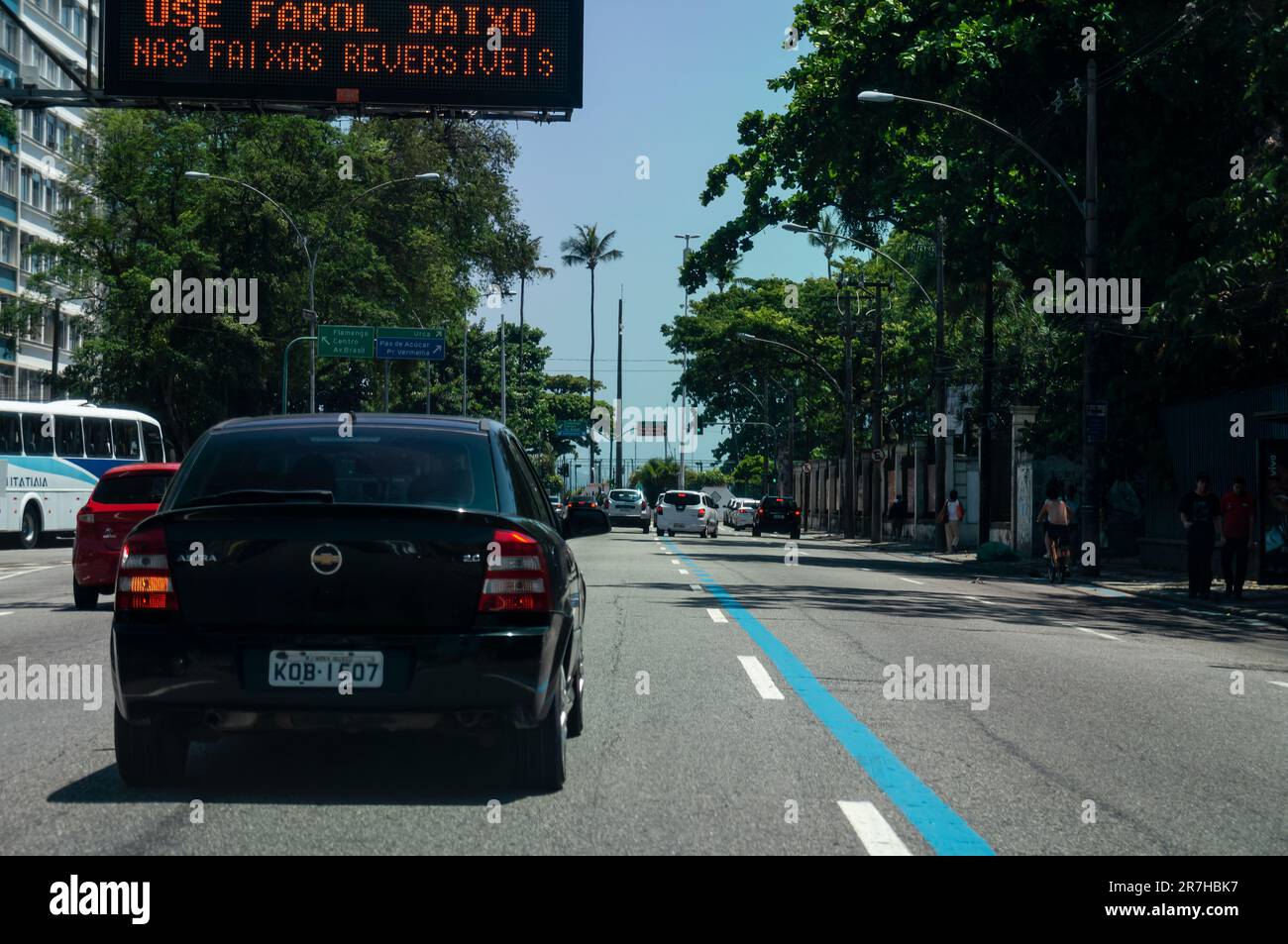 Vue sur l'avenue Venceslau bras avec végétation verte et des voitures passant dans le quartier de Botafogo sous le ciel bleu clair et ensoleillé le matin d'été. Banque D'Images