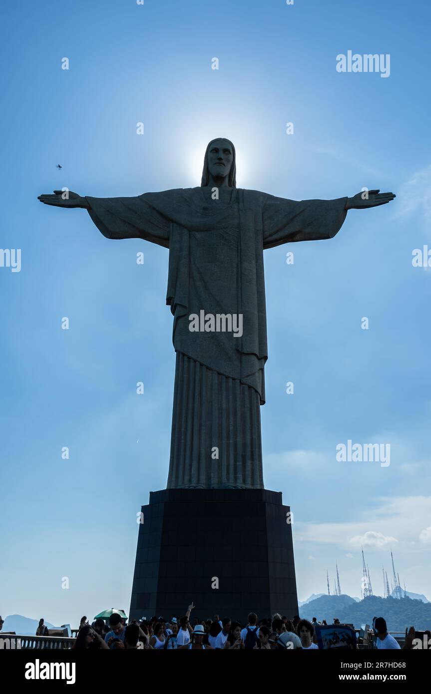 Vue frontale complète de la statue du Christ Rédempteur avec soleil derrière situé sur le sommet de la montagne Corcovado entouré par les touristes sous la journée ensoleillée d'été. Banque D'Images Vue frontale complète de la statue du Christ Rédempteur avec soleil derrière situé sur le sommet de la montagne Corcovado entouré par les touristes sous la journée ensoleillée d'été. Banque D'Images