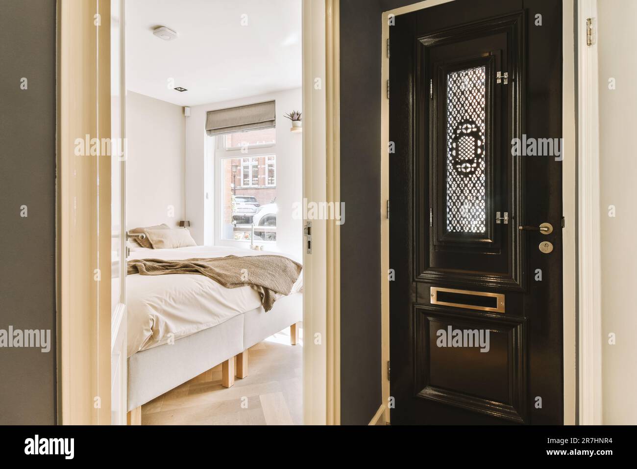 une chambre avec une porte noire et des draps blancs sur le sol devant le lit, il ya une fenêtre ouverte Banque D'Images