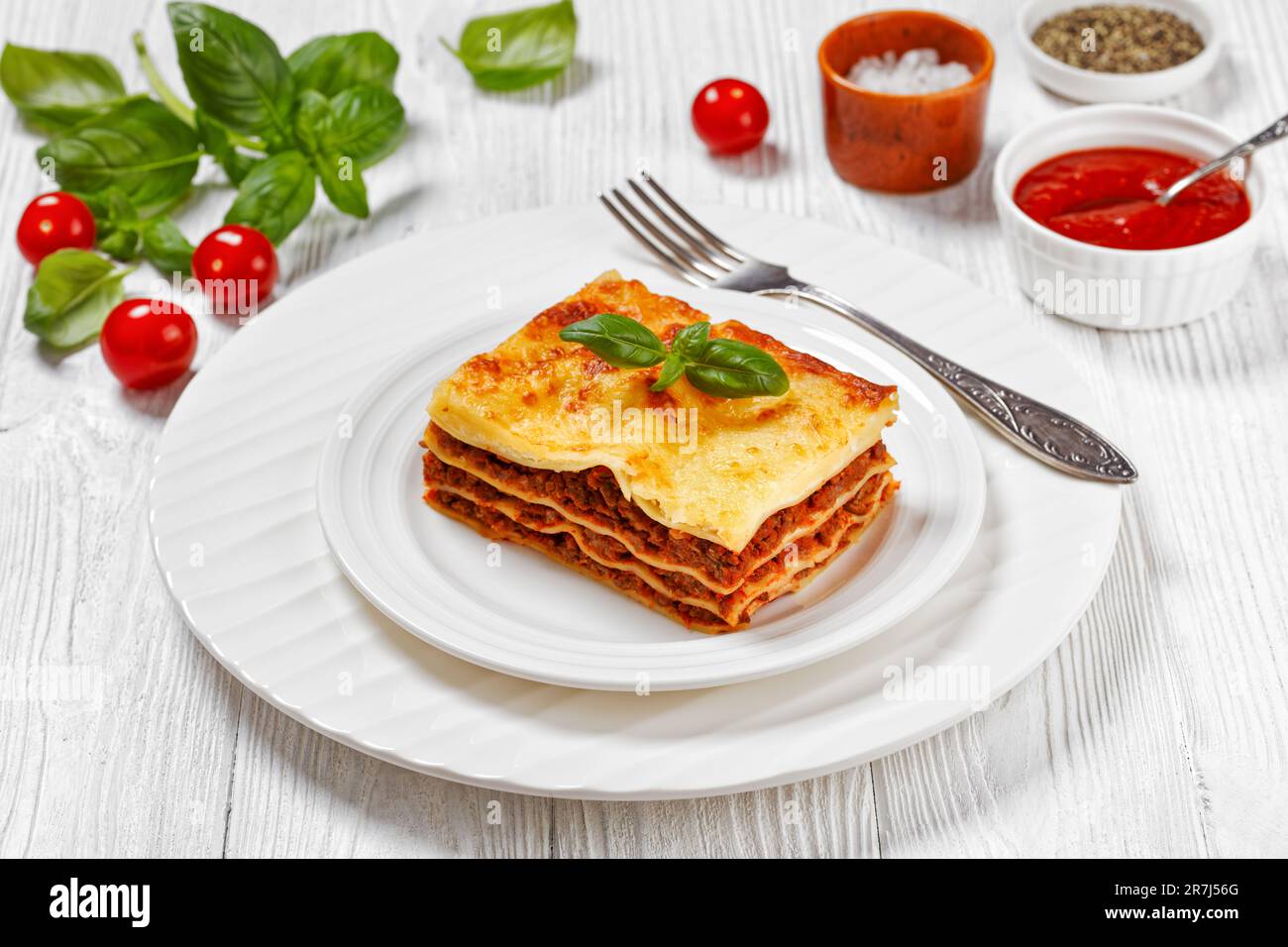 portion de lasagnes al forno, lasagnes de bœuf italien avec du bœuf haché, sauce marinara, nouilles de pâtes et fromage ricotta sur une assiette blanche sur le blanc w. Banque D'Images