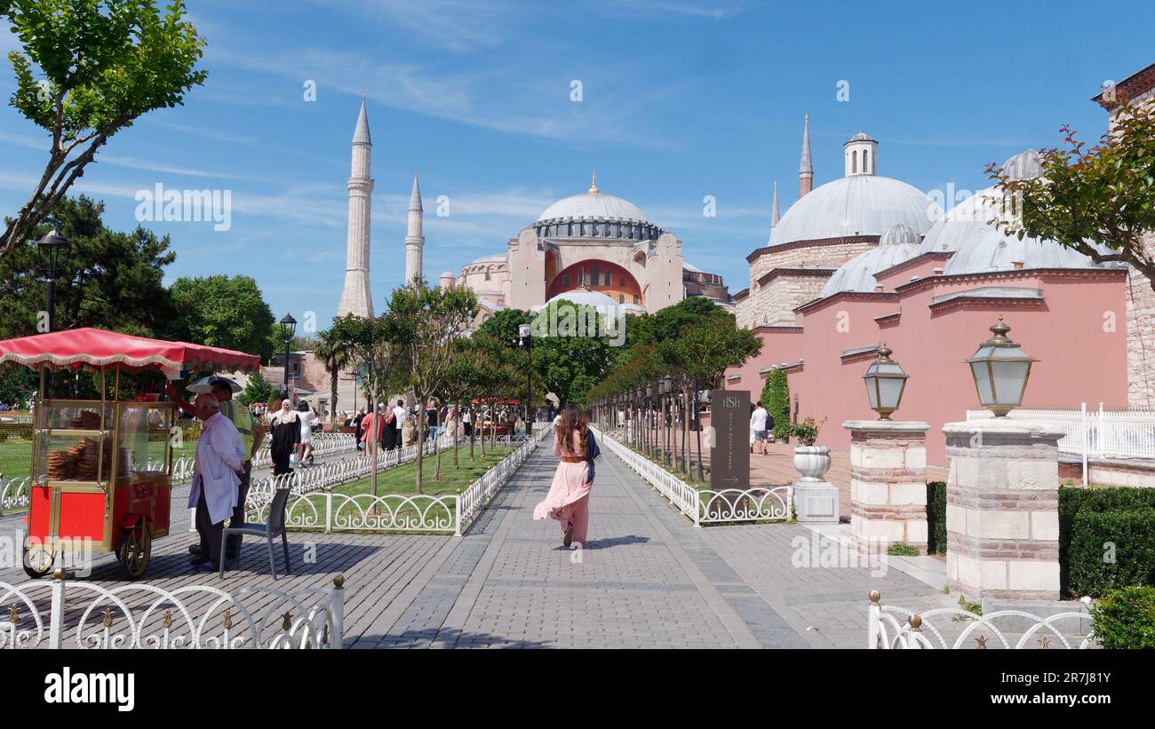 Dame marche le long du chemin vers la mosquée Sainte-Sophie. Le chariot distributeur rouge vend des Simits aka des bagels turcs. Istanbul, Turquie Banque D'Images