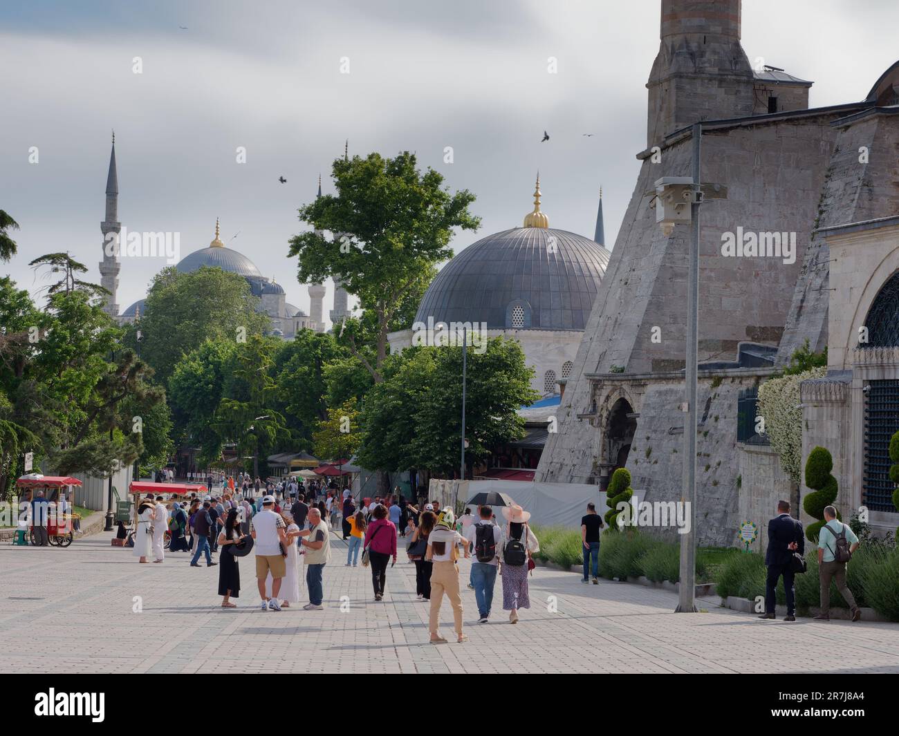 Visiteurs à côté de la mosquée Sainte-Sophie et du Sultan Ahmed (alias Mosquée Bleue), Istanbul, Turquie. Les chariots distributeurs rouges vendent des simit aka des bagels turcs Banque D'Images