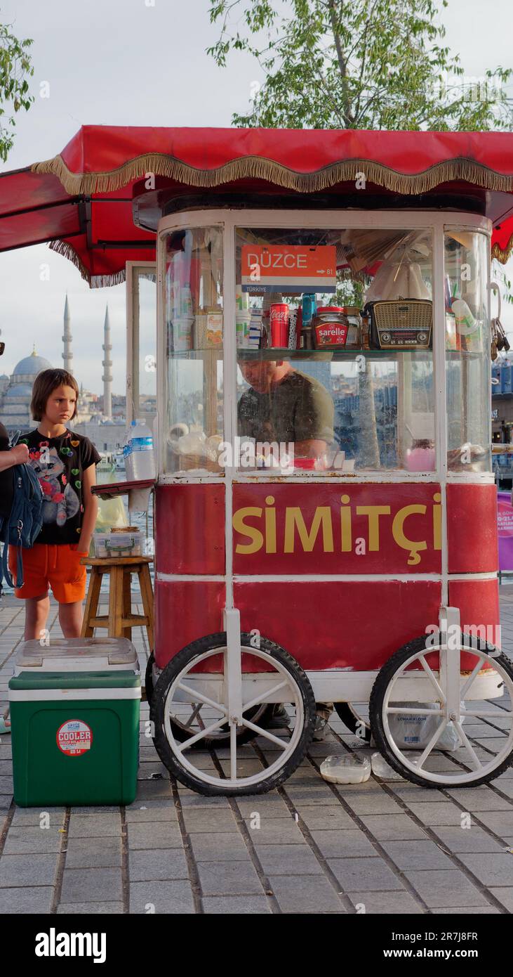 Un jeune client attend près d'un chariot rouge avec une radio rétro à l'intérieur, un soir dans le quartier de Karakoy, Istanbul, Turquie Banque D'Images
