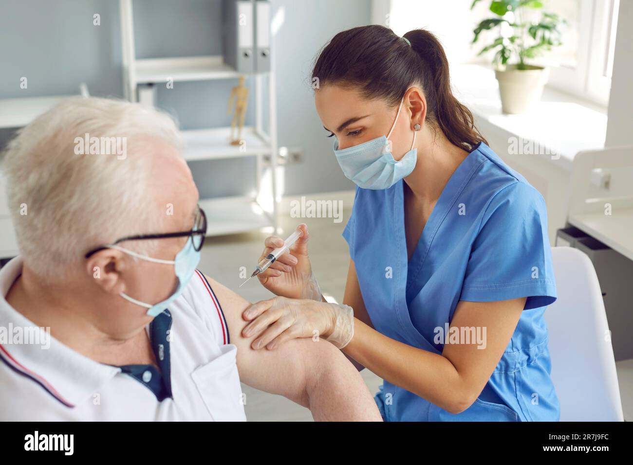 Infirmière administrant un vaccin à un patient âgé de sexe masculin Banque D'Images
