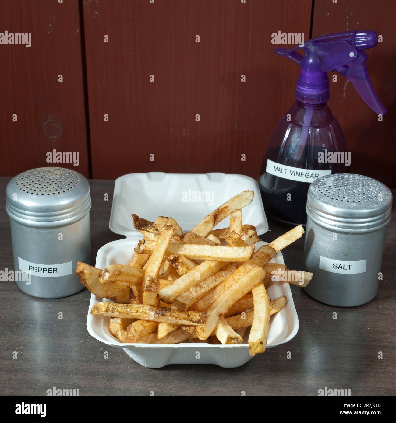 Tous les ingrédients clés pour obtenir des frites parfaites (frites) sont placés sur le comptoir d'un camion à frites local, de frites coupées à la main, de salières et poivrières et de vinaigre de malt dans une bouteille vaporisée, à Elm Banque D'Images