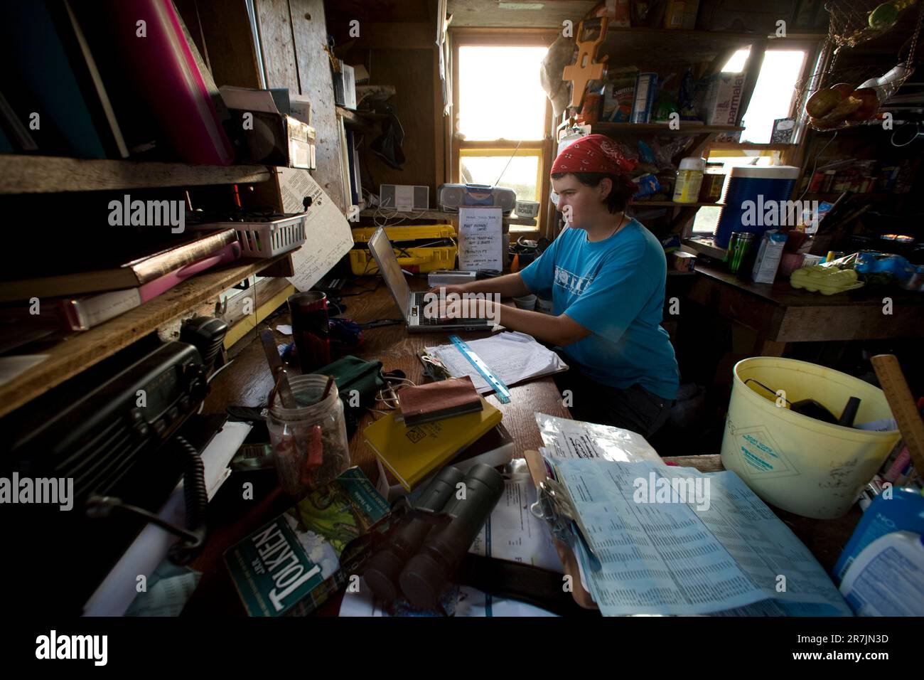 Les chercheurs du projet Puffin Liz Zinsser travaille sur la saisie des données alors que Maki Briggs commence à préparer un dîner dans la cabine du projet Puffin, sur l'île Eastern Egg Rock, dans le Maine. Banque D'Images