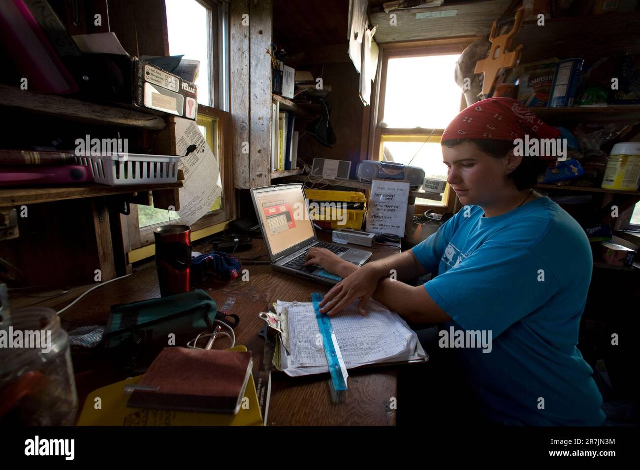 Les chercheurs du projet Puffin Liz Zinsser travaille sur la saisie des données alors que Maki Briggs commence à préparer un dîner dans la cabine du projet Puffin, sur l'île Eastern Egg Rock, dans le Maine. Banque D'Images