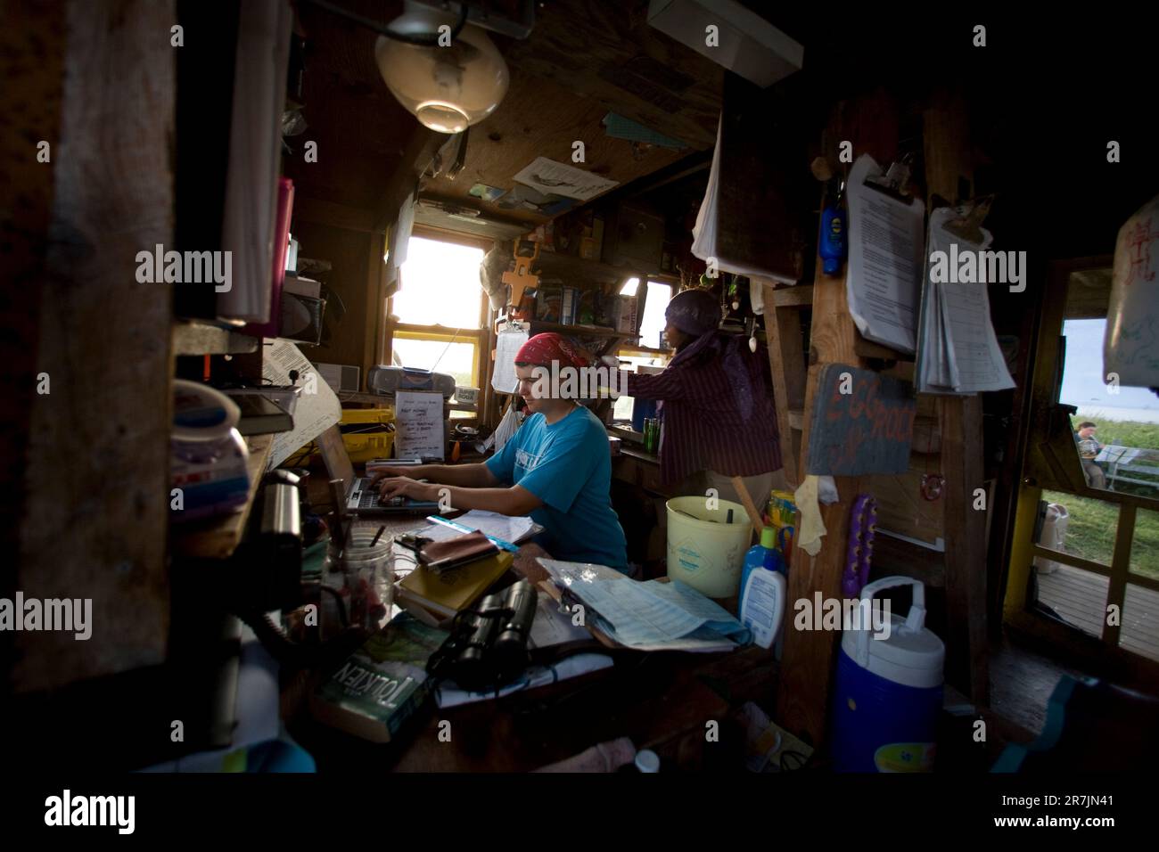 Les chercheurs du projet Puffin Liz Zinsser travaille sur la saisie des données alors que Maki Briggs commence à préparer un dîner dans la cabine du projet Puffin, sur l'île Eastern Egg Rock, dans le Maine. Banque D'Images
