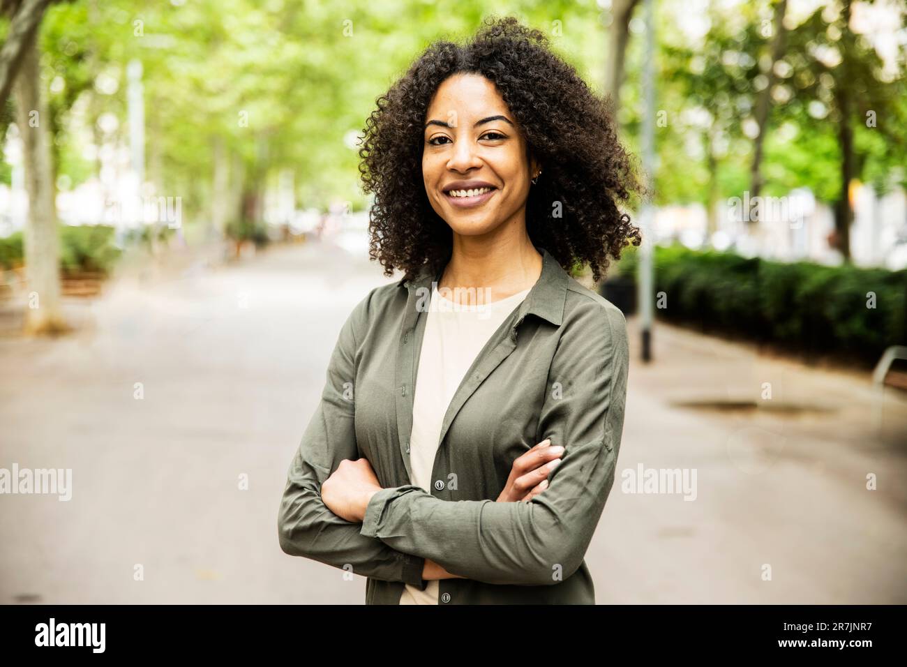 Une femme pleine d'assurance souriant regardant l'appareil photo avec les bras croisés. Banque D'Images