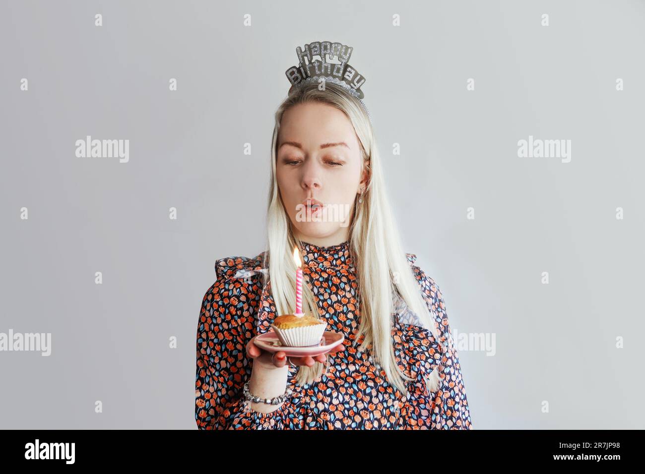 Une fille d'anniversaire souriante souffle la bougie Banque D'Images