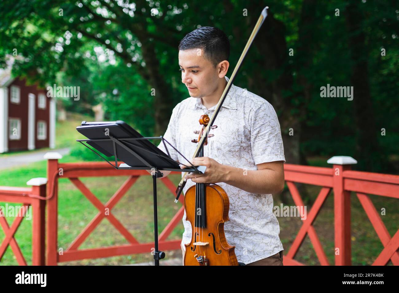 Homme tenant la musique de la feuille de violon au parc Banque D'Images
