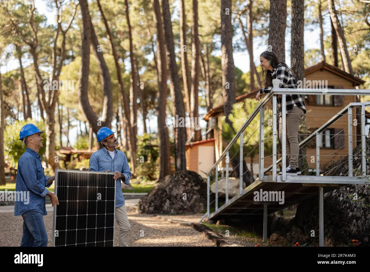 Techniciens photovoltaïques parlant au propriétaire sur la véranda Banque D'Images