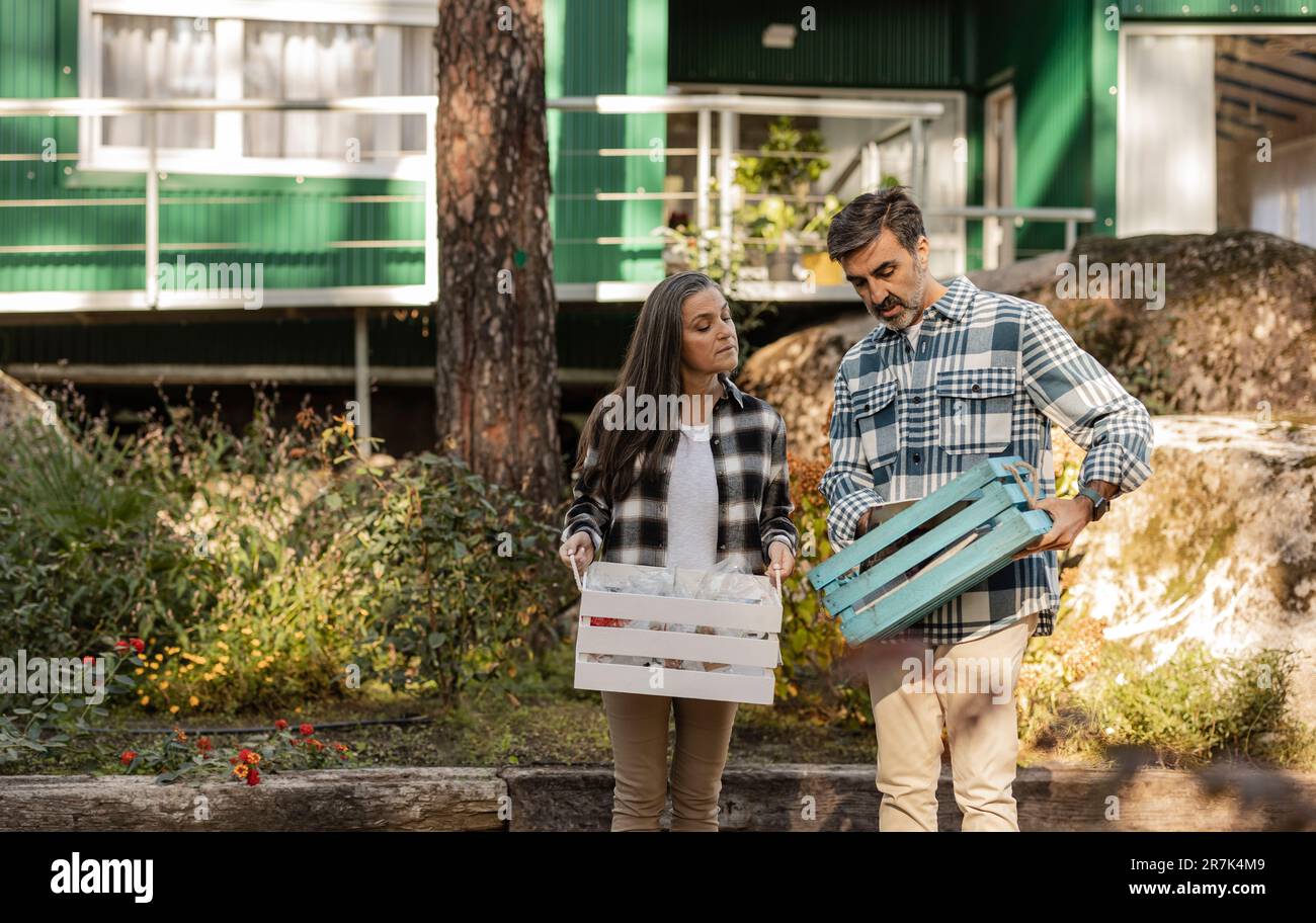 Homme et femme transportant des caisses avec des déchets séparés dans le jardin Banque D'Images