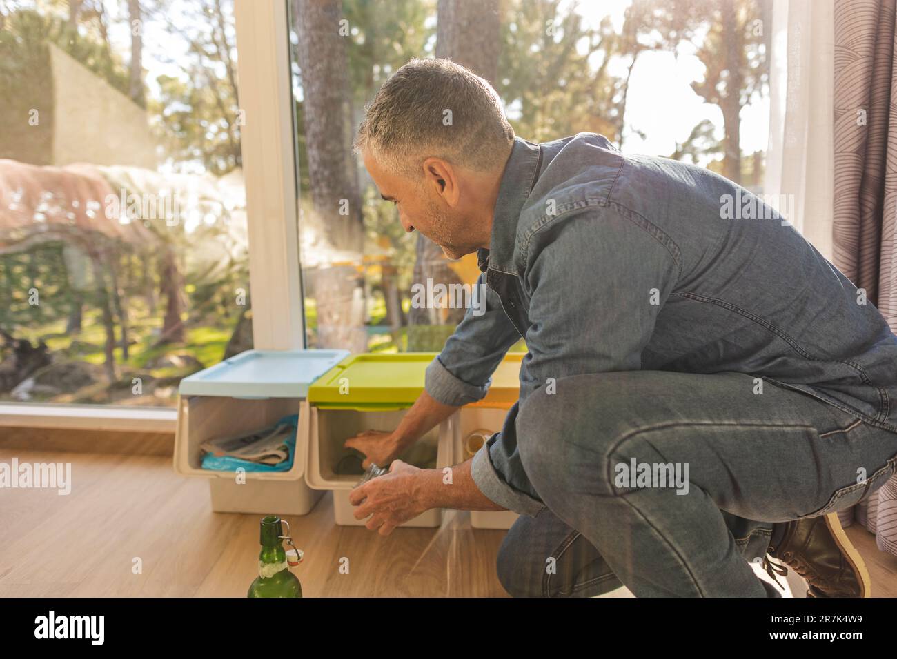 Homme triant les déchets dans le bac de séparation des déchets Banque D'Images