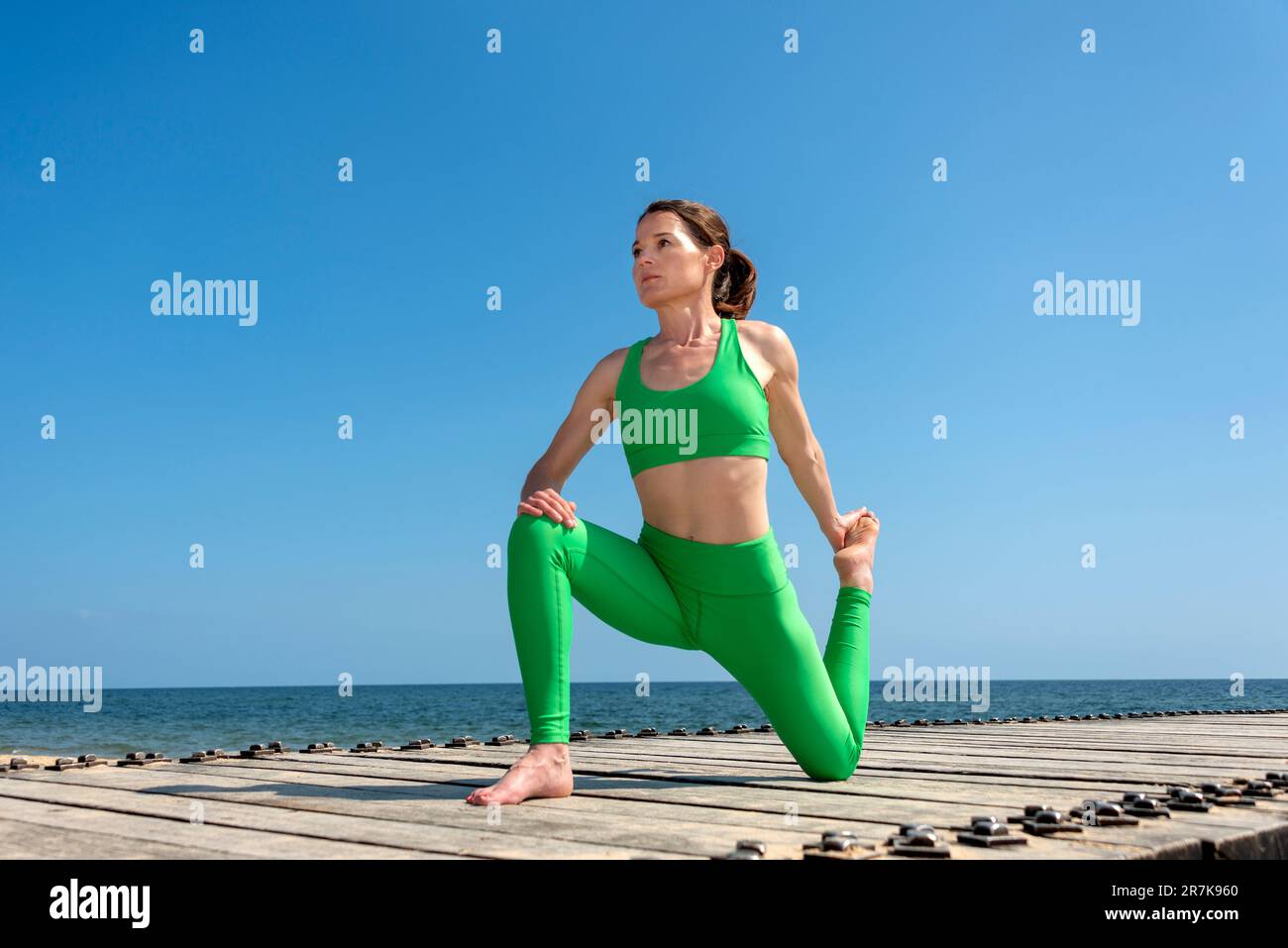 Femme pratiquant le yoga au soleil au bord de la mer, exercices d'étirement. Banque D'Images