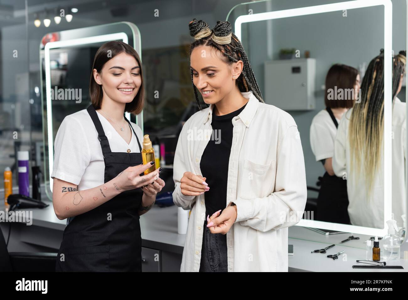 satisfaction de la clientèle, coiffure suggérant de l'huile de cheveux à la cliente féminine, femme heureuse avec des tresses, coiffure, cheveux superposés, cheveux tressés, salon de beauté, ha Banque D'Images