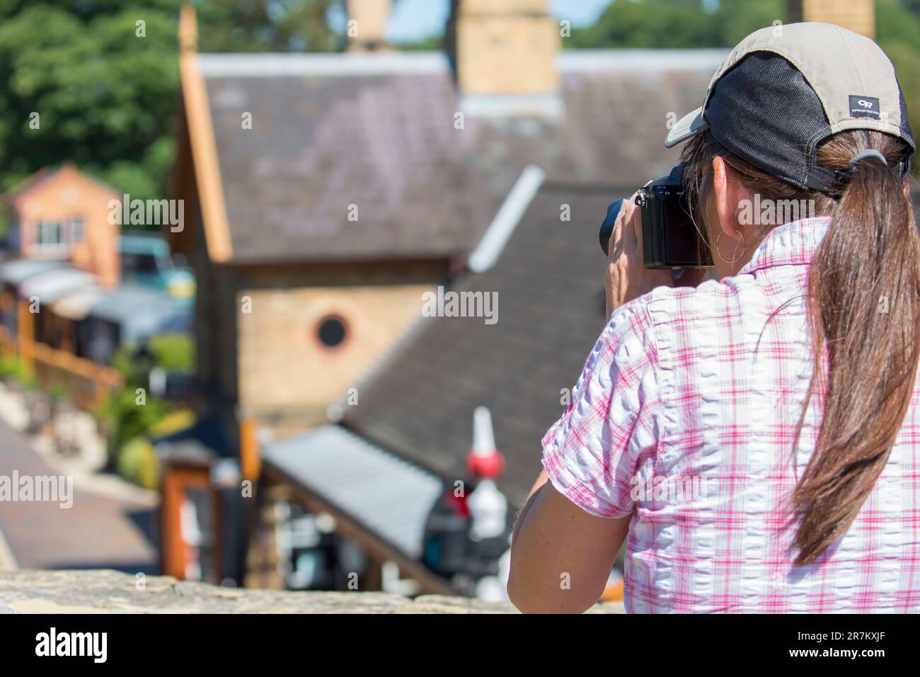 Vue arrière d'une dame qui photographie depuis un pont la gare de la vallée de Severn à Arley Banque D'Images