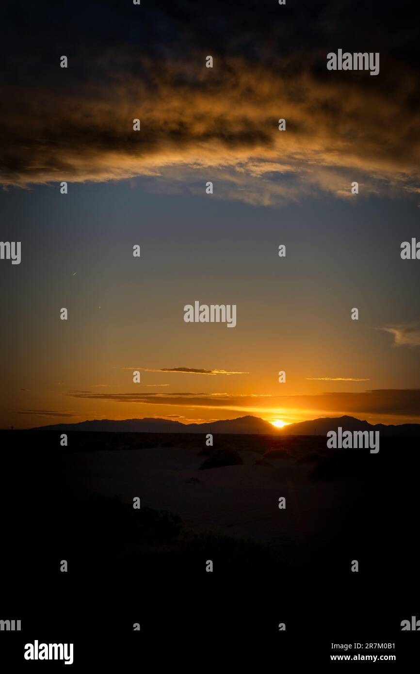 Un coucher de soleil avec des nuages orange derrière les montagnes Franklin, pris près de Horizon City, Texas. Banque D'Images