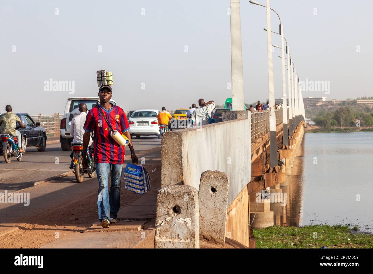 Homme transportant divers objets à la fin de la traversée du fleuve Niger par le Pont des Martyrs à Bamako, Mali. Banque D'Images