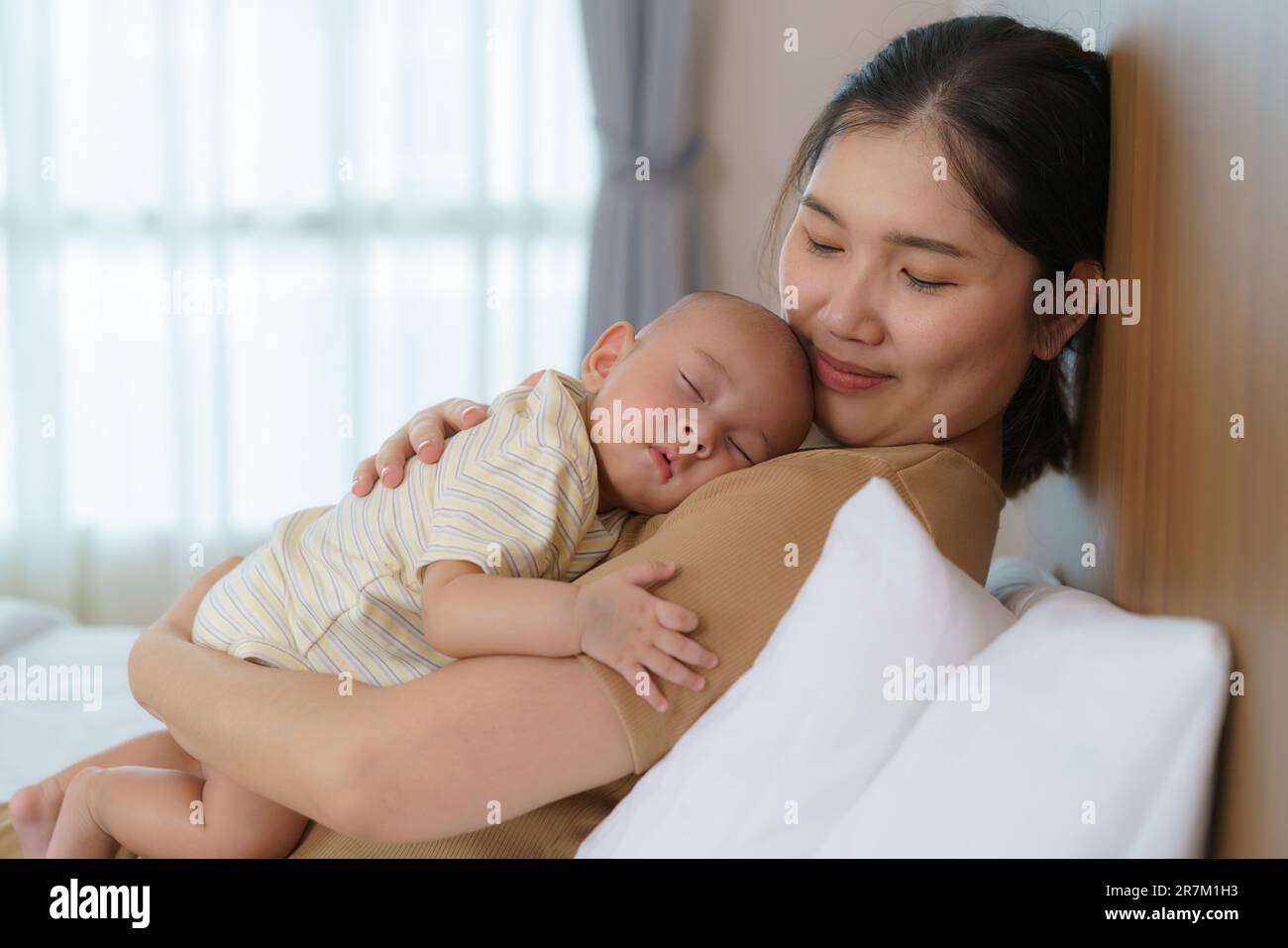 La mère asiatique a embrassé son jeune fils pour qu'elle puisse avoir un bon sommeil dans la chambre à la maison, représente l'amour et la famille Banque D'Images