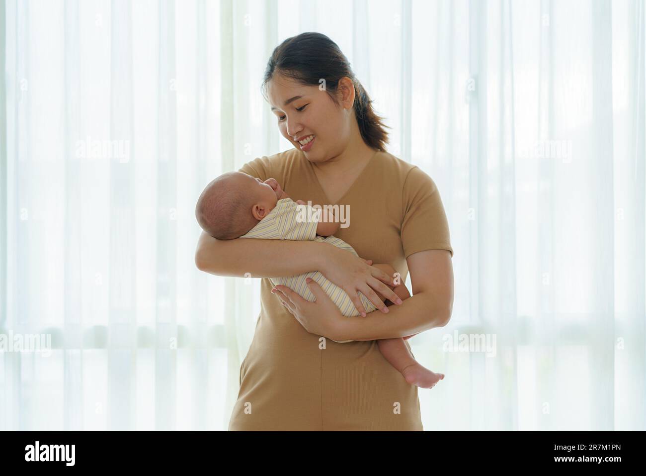 La mère asiatique tient son fils nouveau-né dans la chambre à la maison, représentant l'amour et le lien entre la mère et le fils. Banque D'Images