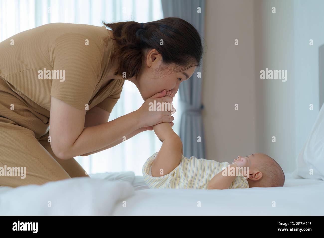 Mère asiatique jouant avec son nouveau-né dans la chambre à la maison. promouvoir les relations familiales et le bon développement du bébé Banque D'Images