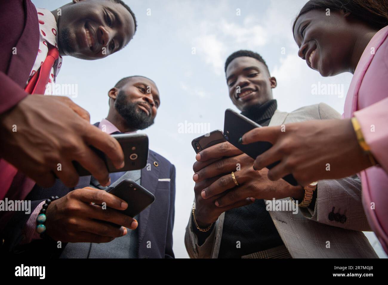 Quatre hommes d'affaires africains utilisent leurs smartphones ensemble, photo vue de dessous Banque D'Images