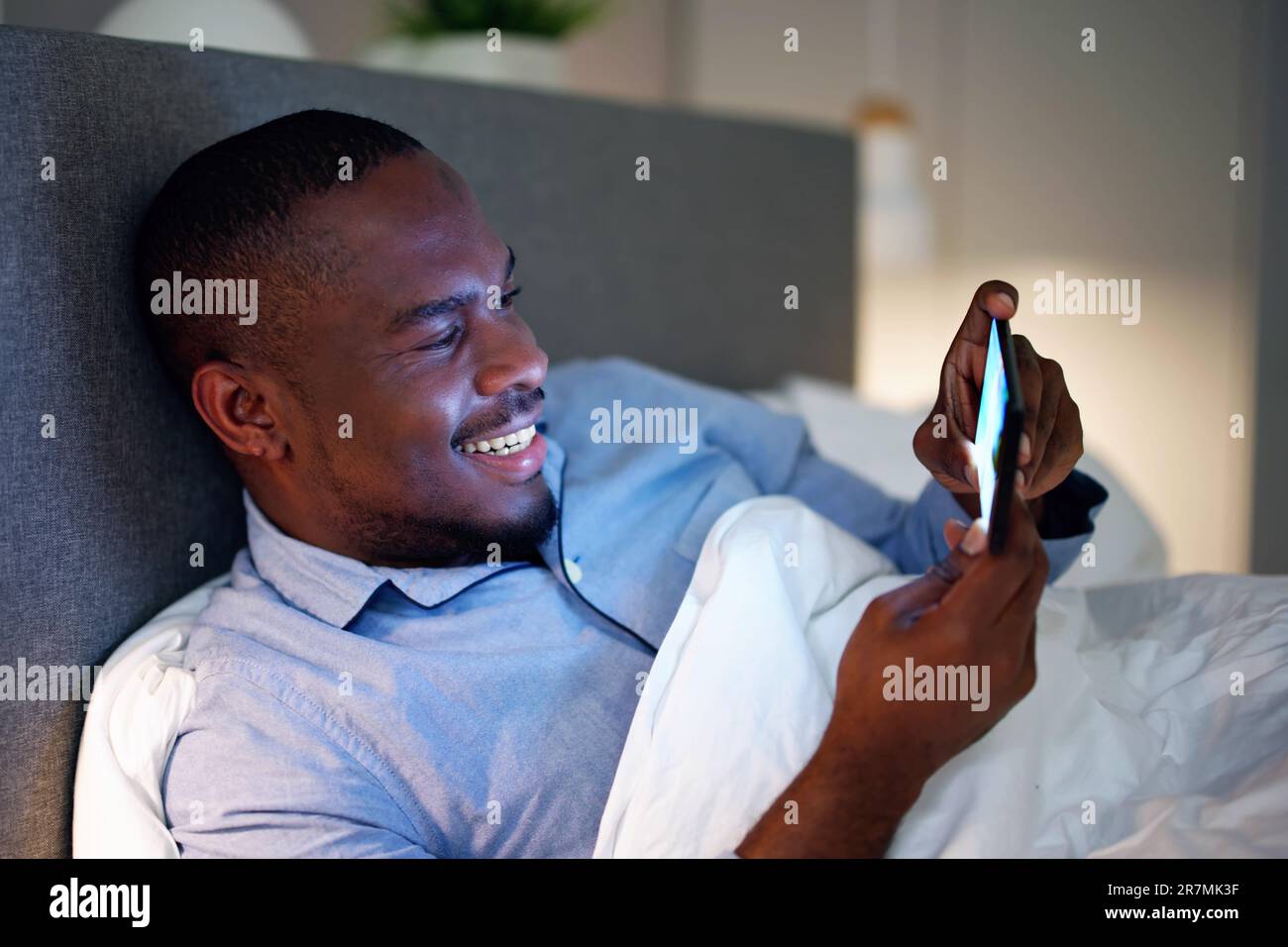 Regarder un téléphone portable avant de dormir la nuit dans la chambre Banque D'Images