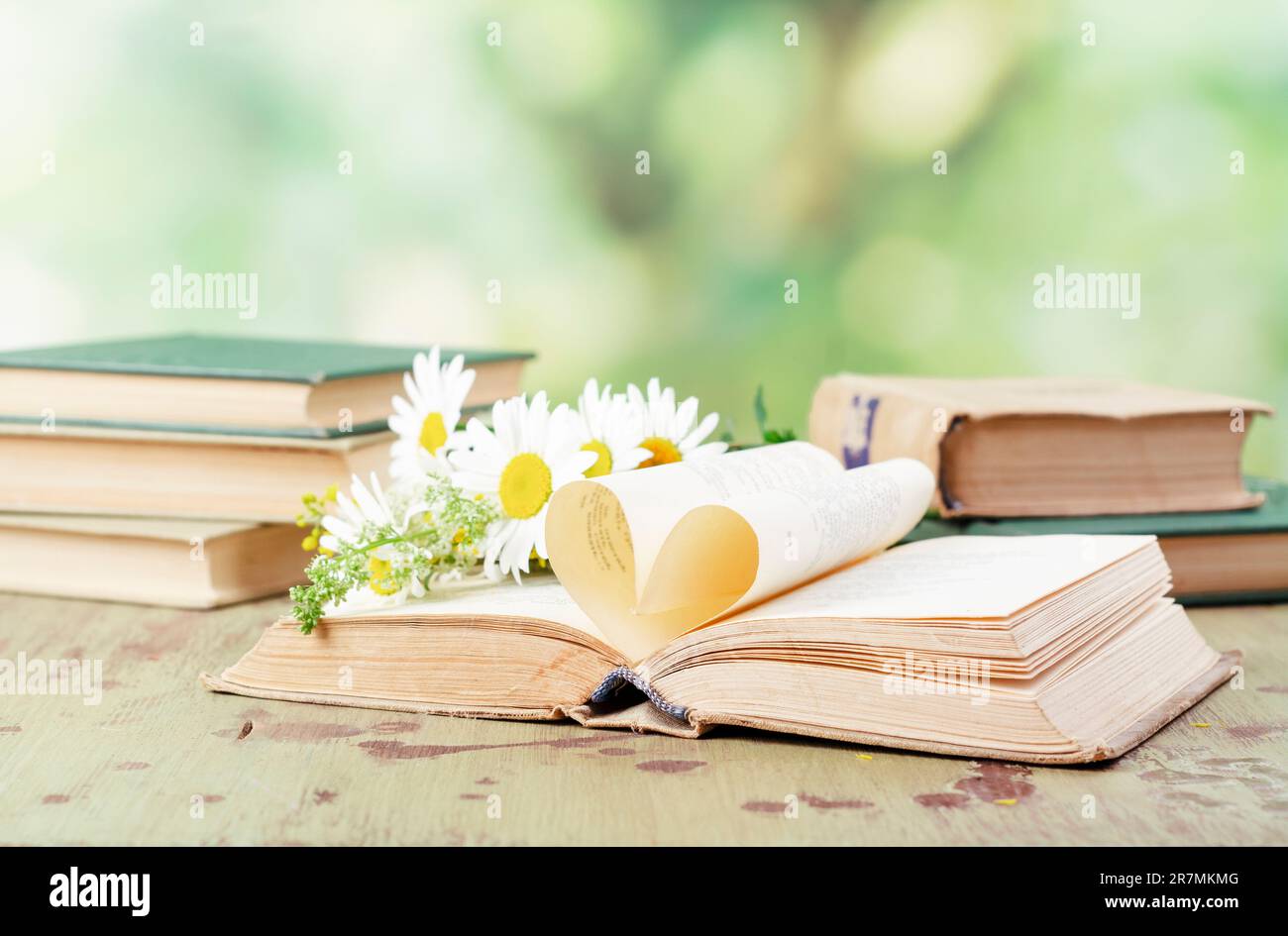 Livre avec des pages ouvertes en forme de coeur et des livres empilés