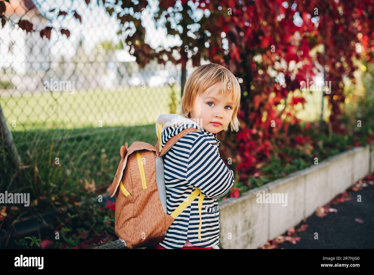 Portrait extérieur d'une petite fille adorable, à vélo, portant un sac à dos Banque D'Images