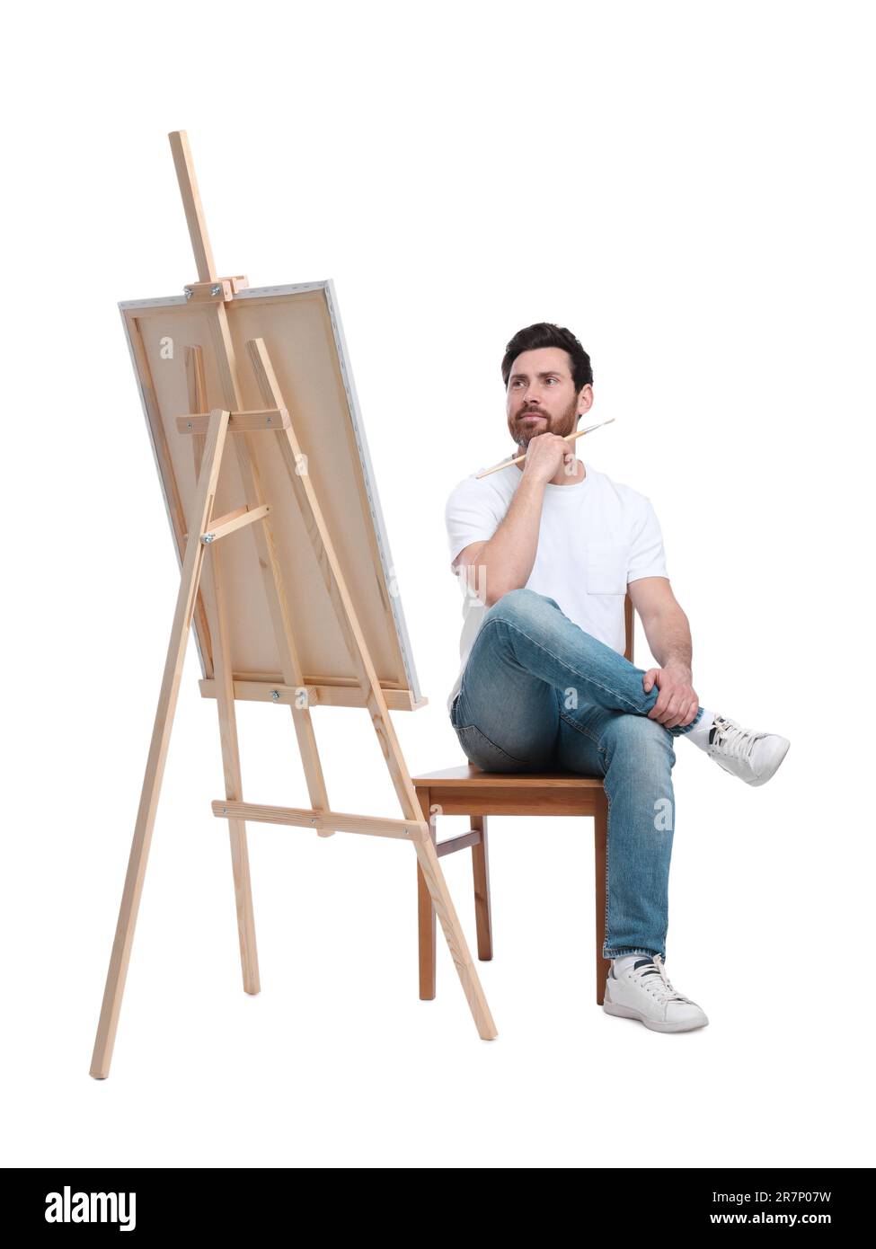 Homme avec peinture au pinceau sur fond blanc. Utilisation du chevalet pour tenir la toile Banque D'Images