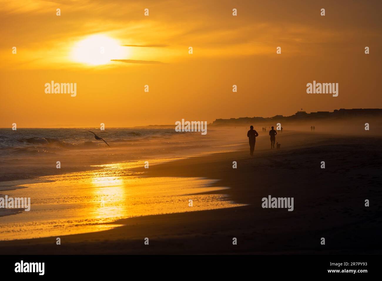 Un groupe de personnes marchant le long de la plage au coucher du soleil sur Emerald Isle, Caroline du Nord Banque D'Images Un groupe de personnes marchant le long de la plage au coucher du soleil sur Emerald Isle, Caroline du Nord Banque D'Images