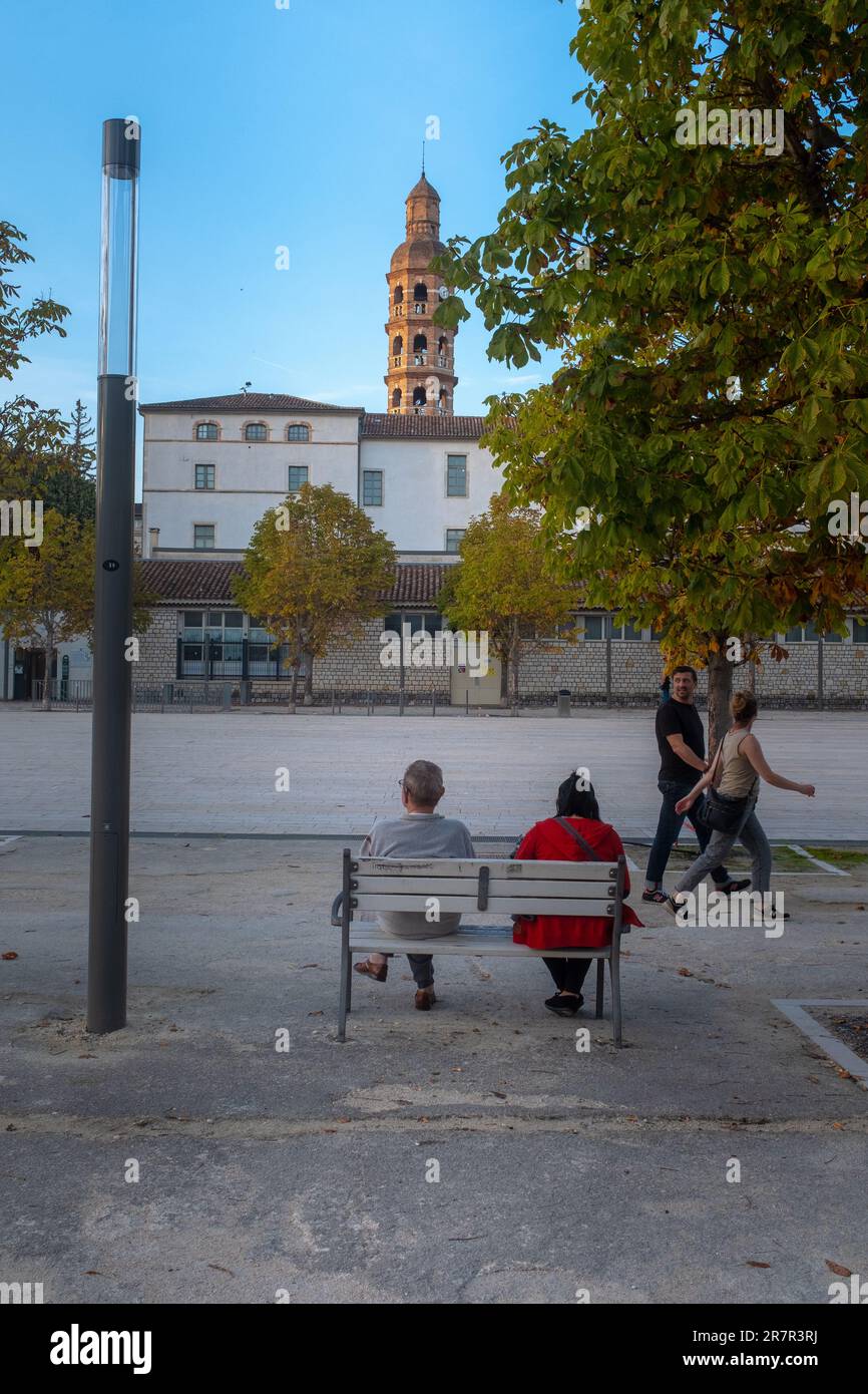 Cahors, France - 29 octobre 2022: Deux personnes assises sur un banc et deux passants en fin de journée sur la place principale de Cahors sur la main Banque D'Images