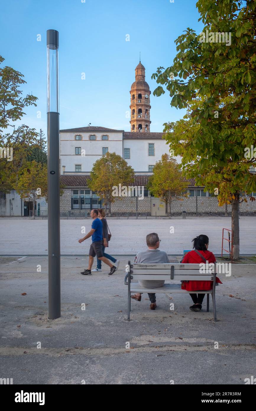 Cahors, France - 29 octobre 2022: Deux personnes assises sur un banc et deux passants en fin de journée sur la place principale de Cahors sur la main Banque D'Images