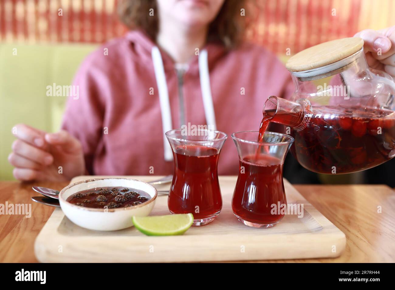 Personne versant du thé de fruits dans des verres d'armudu au restaurant Banque D'Images