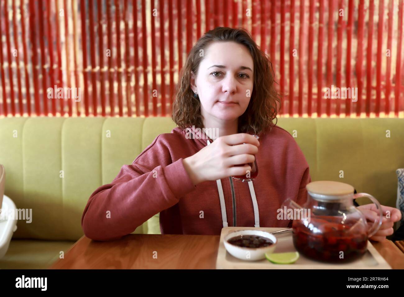 Femme qui boit du thé aux fruits avec de la confiture au restaurant Banque D'Images