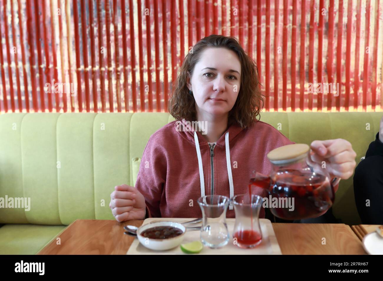 Femme versant du thé de fruits dans des verres d'armudu au restaurant Banque D'Images